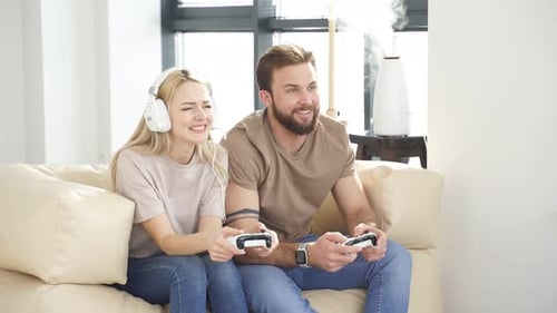 Enthusiastic Couple Play Video Game on Couch Indoors