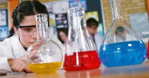 Young Student Observing Chemistry Experiment in Classroom