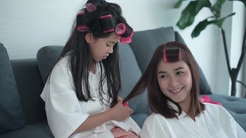 Child Applies Hair Rollers to Smiling Woman