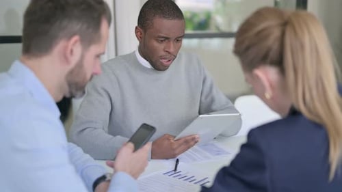Male and Female Businessperson Working on Tablet and Smartphone in Office