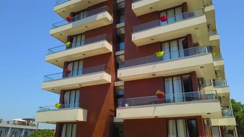 Close-up from drone offers view of modern hotel with many windows and balconies.