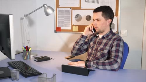 Man Talking on Cell Phone at Office Desk