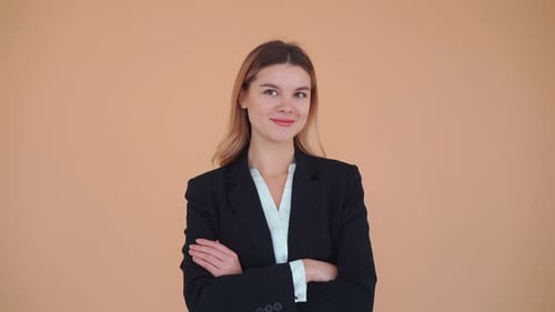 Jeune femme d'affaires vêtue d'une veste noire, d'une chemise blanche, bras croisés sur la poitrine, debout dans un studio