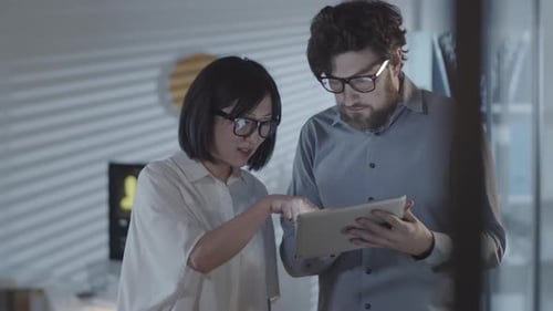 Coworkers with Tablet Discussing Project in Dark Office