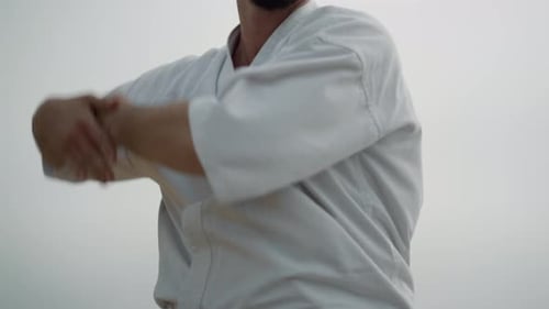 Sportlicher Mann, der Karate am Strand aus nächster Nähe trainiert