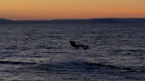 Kiteboarder Glides on the Water During Sunrise