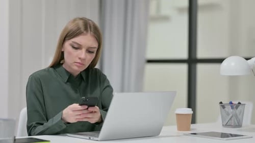 Woman Using Laptop and Smartphone at Desk