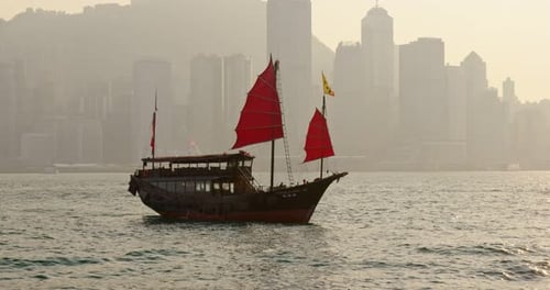 Sunset skyline of Hong Kong with traditional cruise sailboat at Victoria harbor