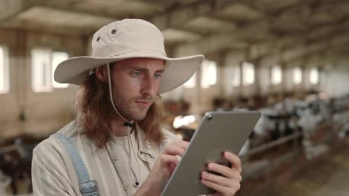 Young Farmer Using Tablet in Goat Barn