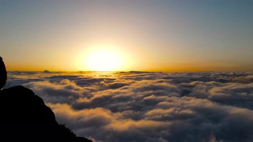 Drone aerial view of mountain peak above the clouds at sunset. Beauty in nature.