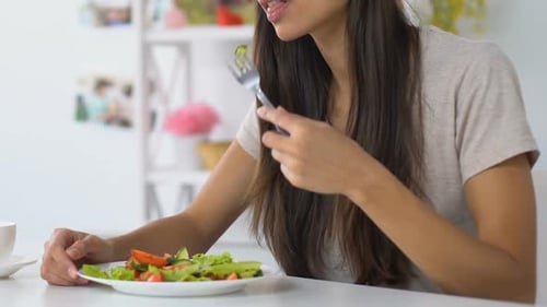 Woman Eats Healthy Salad at Table Indoors