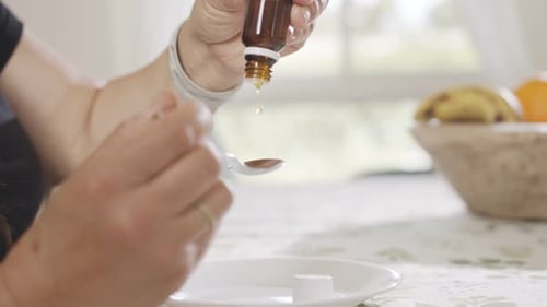 Woman Dosing Liquid Medicine into Spoon, Close Up
