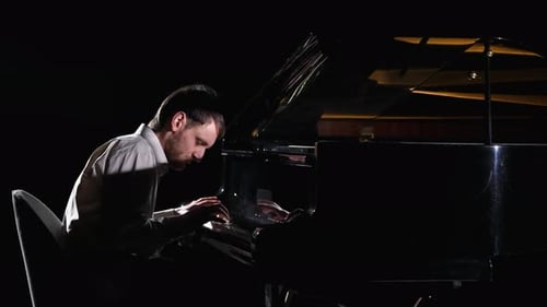 Man Plays a Grand Piano Under Spotlight