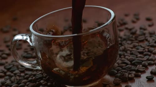 Pouring Coffee into Glass Mug with Coffee Beans