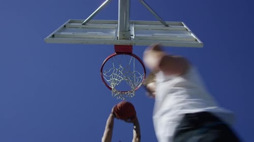 Foto de baixo ângulo em câmera lenta de homem fazendo um slam dunk