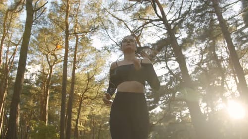 Woman Running Through Sun-Dappled Forest