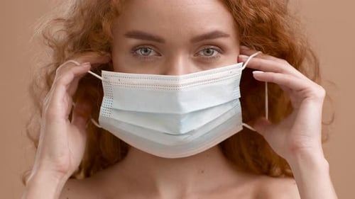 Woman with Red Hair Putting on Face Mask