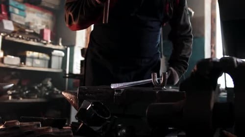 Silhouetted Smithy at the Anvil Working Metal