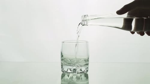 Wasser fließt aus der Flasche ins Glas