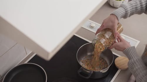 Pouring Lentils Into Pot in Kitchen