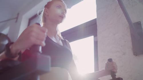 Handheld view of young woman exercising in fitness center. Shot with RED helium camera in 8K