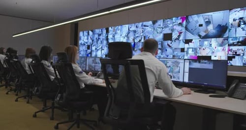 Workers Monitor Security Feeds in Modern Control Room