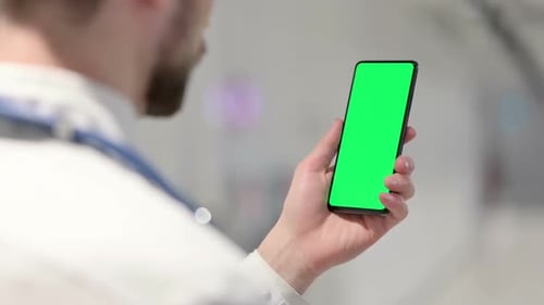 Doctor holding phone with green screen in hospital
