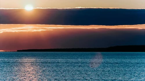 Time-lapse Sun Sets Behind a Cloud - a Red-pink Sunset on the Sea or a Large Lake