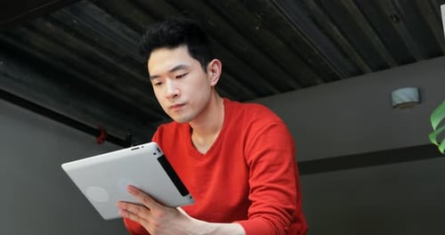 Young Adult Concentrates on Tablet Indoors