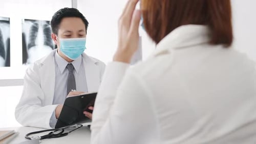Doctor Writes on Clipboard in Medical Exam Room