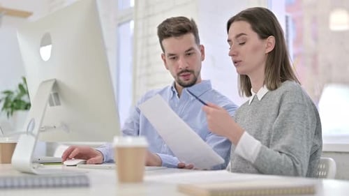 Man and Woman Working Together at Computer in Office