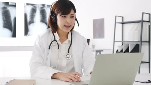 Female Doctor Consults Online Using Laptop and Headset