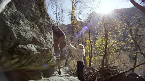 Woman Spotting Man Climbing on Rock