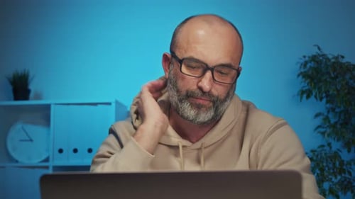 Man Working on Laptop at Desk in Blue Room