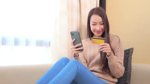 Woman Using Phone and Credit Card on Couch