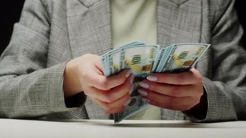 Counting American Hundred Dollar Banknotes on Black Background