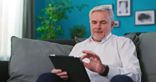Mature Man Using Tablet Device on Couch at Home