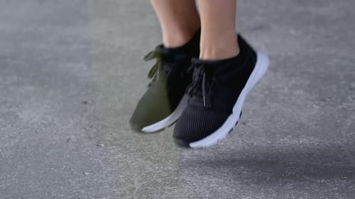 Close-Up of Women's Feet in Sports Shoes Jumping Rope Dressed in Sportswear Black Top