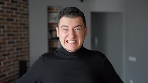 Man is looking at the camera. Then he suddenly starts to grimace. It looks ridiculous and funny
