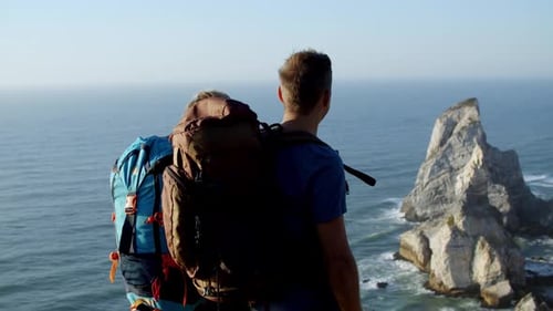 Couple with Camping Backpacks Standing at Cliff