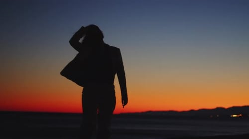 Woman Silhouette Twirling on Beach at Sunset