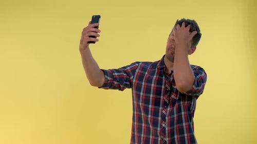 Man Taking Selfies with Smartphone on Yellow Background