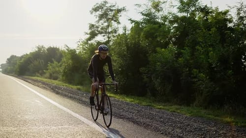 Lone Cyclist Riding on Rural Asphalt Road