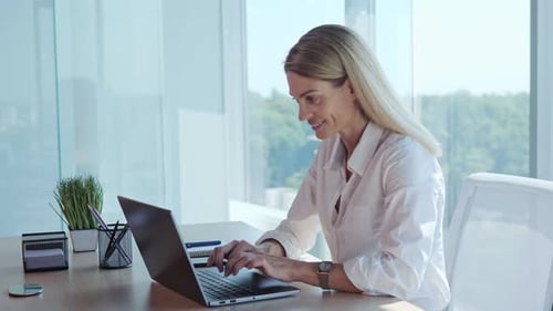 Professional Blonde Business Woman Using Laptop Computer Sits at Workplace