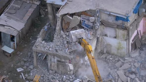 Demolition Excavator Tearing Down Damaged Building in Urban Area