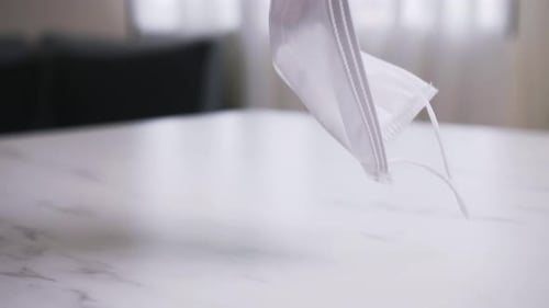 Surgical Mask Falling on a Marble Table