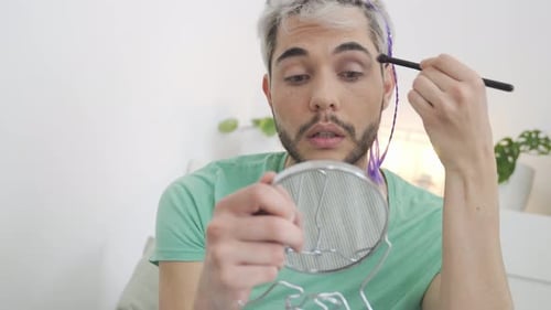 Young Adult Applying Makeup with Brush and Mirror