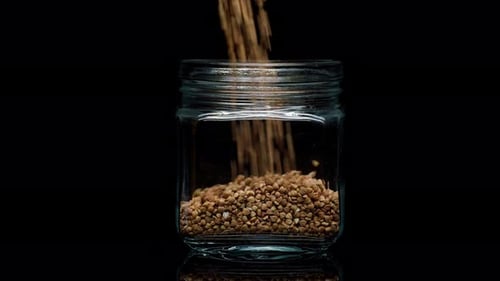 Buckwheat Grains Being Poured Into a Jar