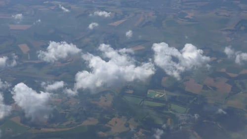 Flugzeugfenster-Ansicht von Wolken, die am Himmel über einer Landschaft schweben