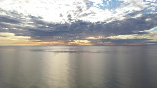 AERIAL: Ascending Pedestal Shot of Horizon and Cumulus Cloudy Sky with Calm Baltic Sea